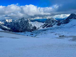 Naklejka premium A stunning view of snow-covered mountain ranges and valleys seen from the top of Zugspitze in Germany. The vast alpine landscape stretches out in a breathtaking winter scene.
