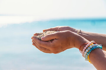 Sand in woman's hands at sea. Selective focus.