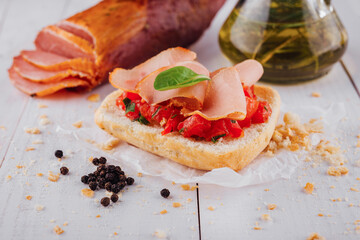 Delicious bruschetta with tomatoes, ham, and basil on white table