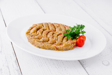 Baba ghanoush decorated with parsley and tomatoes lying on white plate