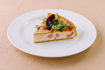 Slice of quiche lorraine resting on a white plate