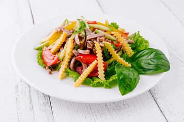 Fresh salad with meat, tomato, cucumber and cheese chips on white plate