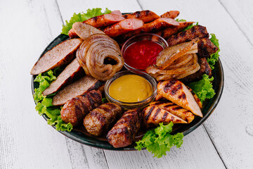 Grilled meat platter with sausages, chicken, and kebabs with dipping sauces