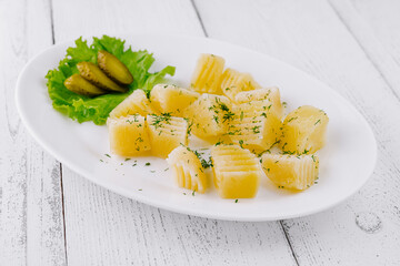 Boiled potatoes with dill and pickles on white plate
