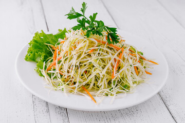 Fresh cabbage salad with carrots and greens on white plate