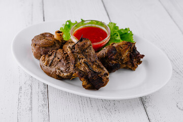 Roasted lamb shanks with rosemary and red spicy sauce on white plate