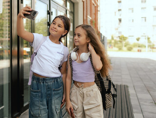 Multiethnic elementary middle school. Girls classmates with backpack in casual clothes take a...