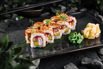 Fresh sushi rolls with eel and avocado being served on black plate