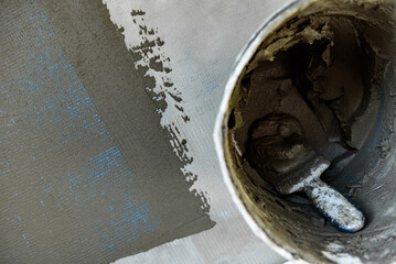 Applying construction glue layer on insulated floor for covering fiberglass reinforcing mesh.