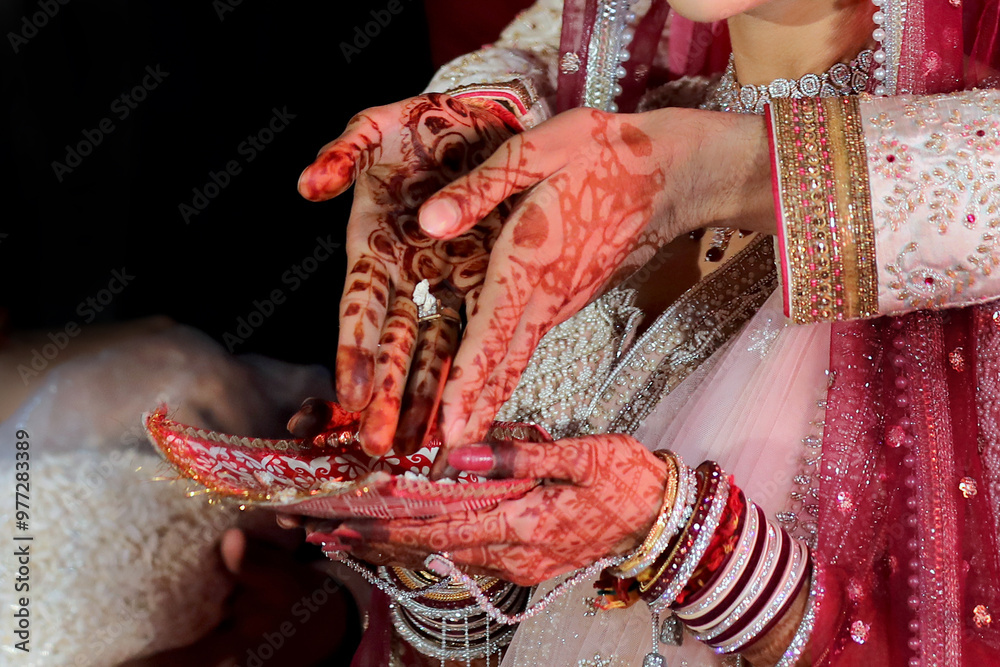 Wall mural a beautiful bride adorned with intricate mehendi designs, delicately performing a traditional indian