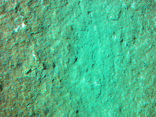 the texture of natural stone is bright green luminescent, similar to a concrete surface,