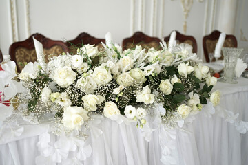 The festive table in the restaurant is decorated with a beautiful bouquet of white flowers.