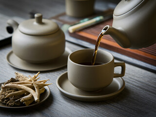 A modern tea set featuring teapot pouring herbal tea into cup, accompanied by herbal ingredients on plate. serene atmosphere evokes sense of calm and relaxation