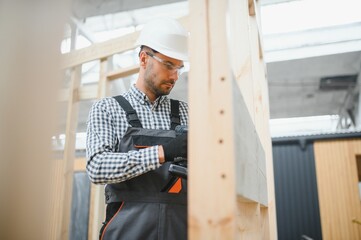 A worker or engineer in a uniform works on a construction site for the manufacture of wooden...