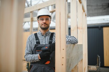 Portrait of a young carpenter worker in a helmet at the construction site of modular houses