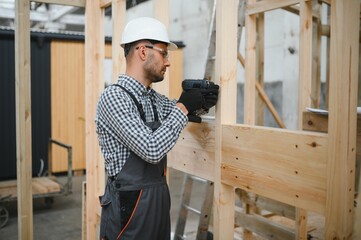 A worker or engineer in a uniform works on a construction site for the manufacture of wooden...