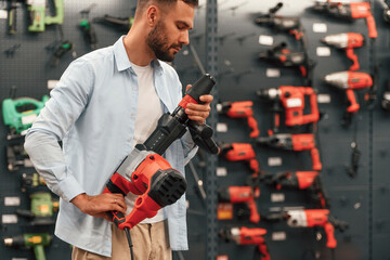 Wall with brand new drills. Man is in the hardware shop