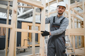 Portrait of a young carpenter worker in a helmet at the construction site of modular houses