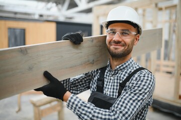 Portrait of a young carpenter worker in a helmet at the construction site of modular houses