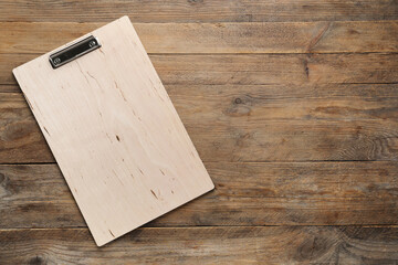 One clipboard on wooden table, top view. Space for text