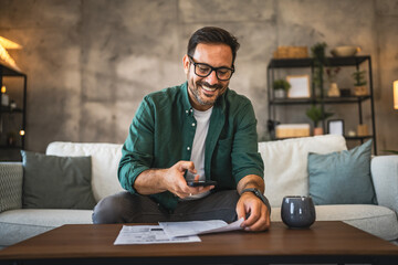 Adult man sit on sofa and have contactless payment bills on cellphone