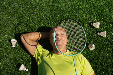 Badminton player resting after game, lying and enjoy on sport court in public park with artificial turf as green grass. Outdoors. Summer sports game. Copy space. View from above
