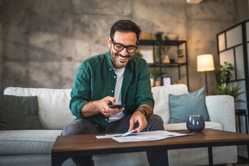 Adult man sit on sofa and have contactless payment bills on cellphone