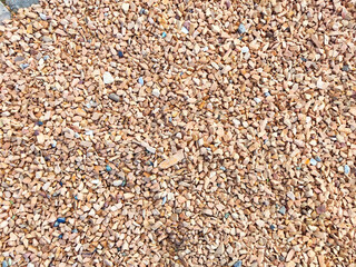 A variety of small, colorful stones lie scattered, reflecting sunlight as they await use in...