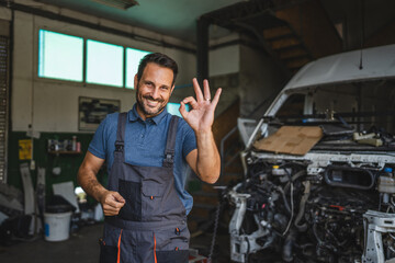 Car mechanic making okay gesture near car with friendly smile