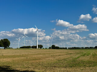 Wind farm windmills set in rural fields with blue sky with clouds