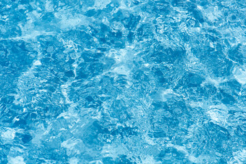 Blue water with ripples on the surface. Defocus blurred transparent blue colored clear calm water surface texture with splashes and bubbles. Water waves with shining pattern texture background.