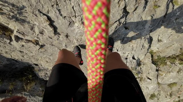 POV of a rock climber rappelling down a tall rock face. High quality 4k footage