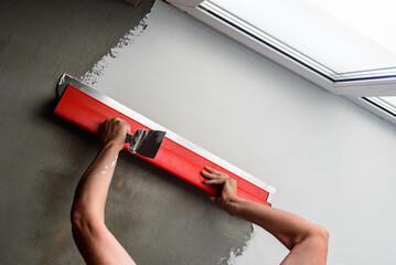 Woman plastering ceiling with finishing putty with putty knife or spatula.