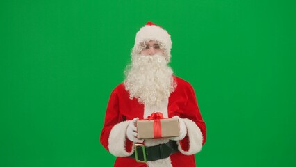 Christmas and New year creative concept. Portrait of man dressed as Santa on chroma key green screen background. Santa Claus in red outfit carrying gift box.