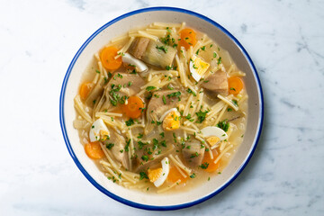 Noodle soup with carrots, artichokes and egg. Top view table.