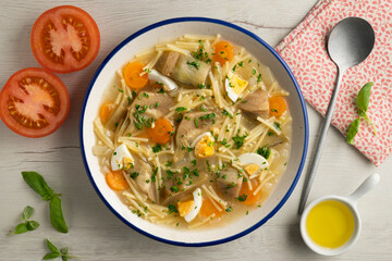 Noodle soup with carrots, artichokes and egg. Top view table.