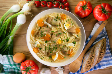 Noodle soup with carrots, artichokes and egg. Top view table.