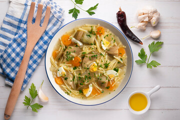 Noodle soup with carrots, artichokes and egg. Top view table.