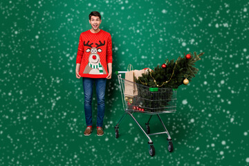 Full size photo of young man happy positive smile show jumper trolley shopping new year eve...