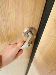 The person presses the door handle with his hand and opens the door to the room. Lock and security, privacy. Entrance to the apartment, to the house. Using the texture and background of the tree 