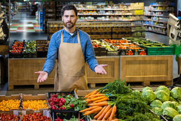 Confident grocery store employee stands in produce section showcasing fresh vegetables. Vibrant colors of carrots, radishes, cherry tomatoes surround worker.