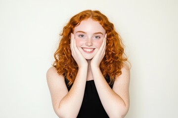 Fototapeta premium Against a plain white background, a child holds hands to their faces and looks at the camera