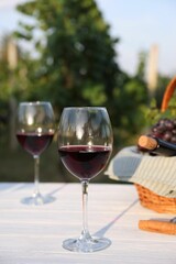 Tasty wine in glasses on white wooden table outdoors