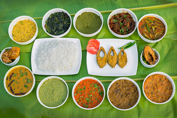 Traditional Bengali dishes such as bhorta, bhaji, fish curry, and vegetable curry are served in white ceramic pots and with Banana leaves.