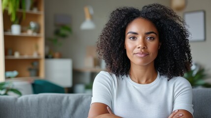 A confident woman stands alone with her arms crossed, displaying a poised expression in an elegant modern interior, embodying strength and independence.