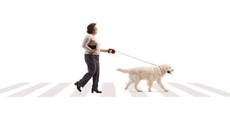 Full length profile shot of a mature woman crossing a street with a dog