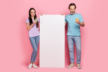 Full length portrait of two partners use telephone chatting blogging empty space ui menu isolated on pink color background