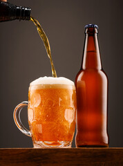 A bottle of beer and a glass of beer on a dark background.