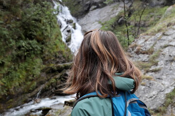 Naklejka premium Girl from behind admires the Lenteney Waterfall in La Salle in Aosta Valley, Italy.
