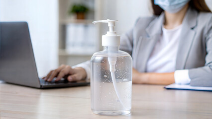 Fototapeta premium Hand sanitizer bottle on desk in office setting during covid pandemic